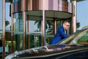 a man in a blue suit standing next to a car at Hilton Guangzhou Baiyun - Canton Fair Free Shuttle Bus, 3km to Yuexiu District in Guangzhou