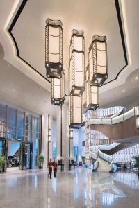a lobby with escalators and chandeliers in a building at Conrad Guangzhou - Free shuttle between hotel and Exhibition Center during Canton Fair & Exhibitor registration Counter in Guangzhou