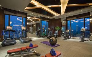einen Fitnessraum mit Kardiogeräten in einem Gebäude mit Fenstern in der Unterkunft Hilton Changzhou in Changzhou