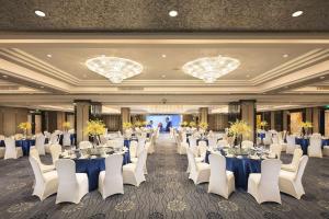 a banquet hall with tables and white chairs and chandeliers at Hilton Foshan in Foshan