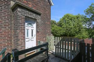 a brick building with a white door and a wooden fence at 2 bedroom house in Belfast with garden in Belfast
