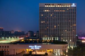 Hilton Hefei في خفي: مبنى كبير مع علامة مضاءة أمامه