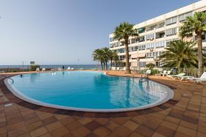 a large swimming pool in front of a hotel at RENOVADO APARTAMENTO 1º LINEA DE MAR in San Agustin
