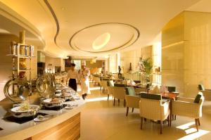 a restaurant with a long counter with tables and chairs at Hilton Hefei in Hefei