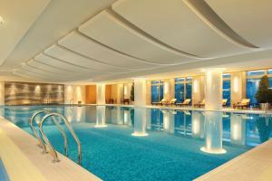 een groot zwembad in een hotel met tafels en stoelen bij DoubleTree by Hilton Hangzhou East in Hangzhou
