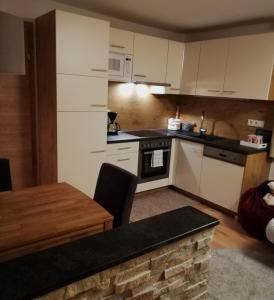 a kitchen with white cabinets and a wooden table at Dreilärchenhaus in Brixen im Thale