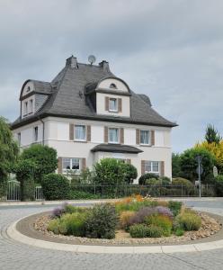 ein großes weißes Haus mit einem Gameradach in der Unterkunft Elena Kempf Haaratelier & Guesthouse in Braunfels