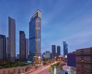 un edificio alto con un cartel en una ciudad en Hilton Shenyang en Shenyang
