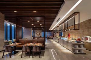 a restaurant with tables and chairs and a counter at Hilton Shenyang in Shenyang
