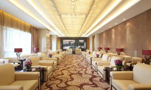 DoubleTree by Hilton Wuhu في Wuhu: غرفة انتظار كبيرة مع كراسي وطاولات