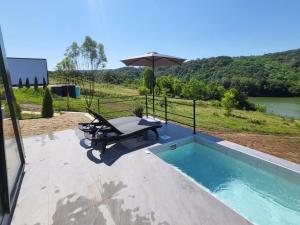 a pool with a picnic table and an umbrella at Glamping A frame lake in Barajevo