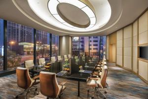 a dining room with tables and chairs and a large window at Hilton Shenyang in Shenyang