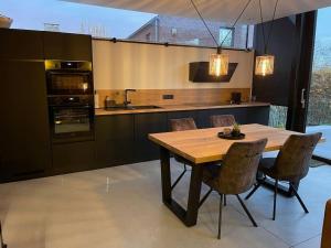 a kitchen with a wooden table with chairs and an oven at Gîte 'Au bout du Tige' in Braives