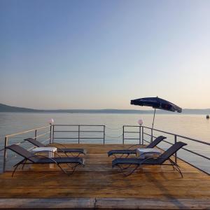 two lounge chairs and an umbrella on a dock at Casa Alexia in Coronini