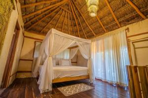 Cama en habitación con techo de madera en SelvaLuz Tulum Resort & Spa, en Tulum