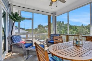 eine abgeschirmte Veranda mit einem Tisch und Stühlen in der Unterkunft Fruitcakes in St. George Island