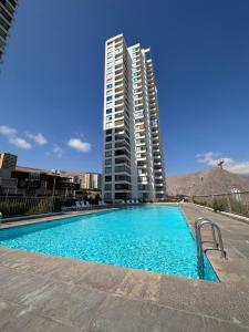 ein Schwimmbad vor einem hohen Gebäude in der Unterkunft Departamento 1D1B Condominio Altos de Huayquique in Iquique