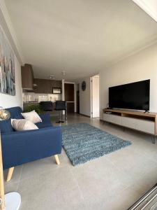 ein Wohnzimmer mit einem blauen Sofa und einem Flachbild-TV in der Unterkunft Departamento 1D1B Condominio Altos de Huayquique in Iquique