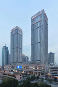 two tall buildings in a city with a parking lot at Hilton Zhongshan Downtown in Zhongshan