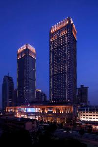two tall buildings in a city at night at Hilton Zhongshan Downtown in Zhongshan