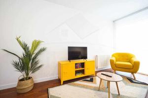 a living room with a yellow chair and a tv at La Luca Apartamento in Llanes