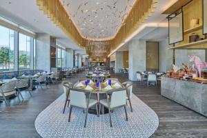 a dining room with tables and chairs and windows at Doubletree By Hilton Shenzhen Airport in Bao'an