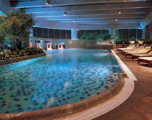 a large swimming pool in a building with chairs at Hilton Chongqing in Chongqing