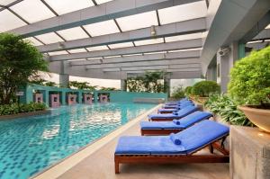重慶的住宿－重慶希爾頓酒店，大楼内一个带蓝色躺椅的游泳池