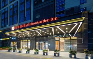 een gebouw met een bord dat de miljoenen Garden Inn leest bij Hilton Garden Inn Shenzhen Nanshan Avenue in Shenzhen