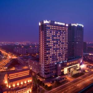 un edificio alto con luces encendidas en una ciudad por la noche en DoubleTree By Hilton Wuxi, en Wuxi