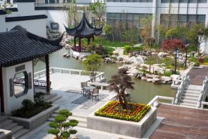 DoubleTree By Hilton Wuxi في ووشي: حديقة بها شرفة وبركة