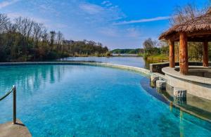 uma piscina com um gazebo ao lado de um rio em Lushan West Sea Resort, Curio Collection by Hilton em Jiujiang