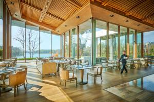 a person walking in a restaurant with tables and chairs at Lushan West Sea Resort, Curio Collection by Hilton in Jiujiang