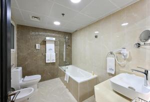 a bathroom with a toilet and a sink and a tub at Saray Musheireb Hotel Suites and Apartment in Doha