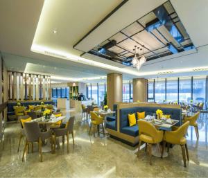 a restaurant with tables and chairs in a room with windows at Hilton Garden Inn Zhongshan Guzhen in Zhongshan