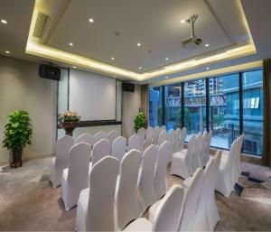 a conference room with white chairs and a projection screen at Hilton Garden Inn Zhongshan Guzhen in Zhongshan