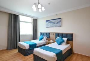 a hotel room with two beds and a chandelier at Saray Musheireb Hotel Suites and Apartment in Doha
