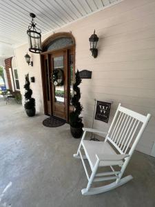ein weißer Schaukelstuhl auf der Veranda eines Hauses in der Unterkunft Opus House Historic Natchitoches in Natchitoches