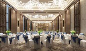 a banquet hall with white tables and chairs and chandeliers at Hilton Garden Inn Heze in Heze