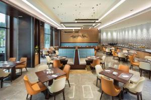 a restaurant with tables and chairs and a bar at Hilton Garden Inn Shiyan in Shiyan