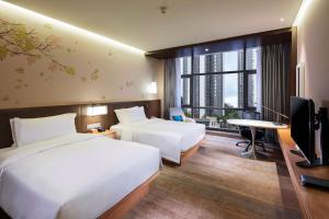 um quarto de hotel com duas camas e uma televisão em Hilton Garden Inn Shiyan em Shiyan