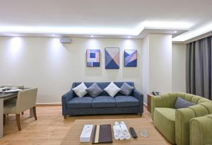 a living room with a blue couch and a table at Saray Musheireb Hotel Suites and Apartment in Doha
