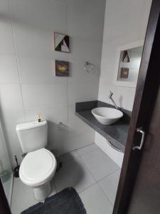 La salle de bains blanche est pourvue de toilettes et d'un lavabo. dans l'établissement Pousada Tio Pietro, à Imbituba