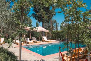 a pool at a resort with lounge chairs and trees at Villa Cesi Resort & Spa in Impruneta