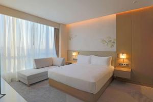sypialnia z łóżkiem, kanapą i oknem w obiekcie Hilton Garden Inn Changzhou Jintan w mieście Changzhou