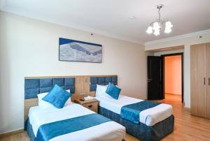 a hotel room with two beds with blue pillows at Saray Musheireb Hotel Suites and Apartment in Doha
