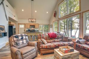 a living room with couches and chairs and a kitchen at Cozy Northwoods Cabin with Private Lake Access in Eagle River