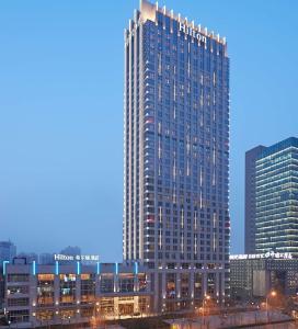 um edifício alto numa cidade à noite em Hilton Zhengzhou em Zhengzhou