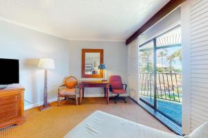 1 dormitorio con escritorio, sillas y ventana grande en Condos in Kauai Beach Resort, en Hanamaulu