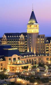 un gran edificio con una torre de reloj por la noche en Hilton Qingdao Golden Beach - Beer Halls, en Huangdao